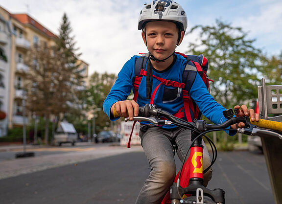 Ein Junge mit Schulranzen fährt mit dem Rad.