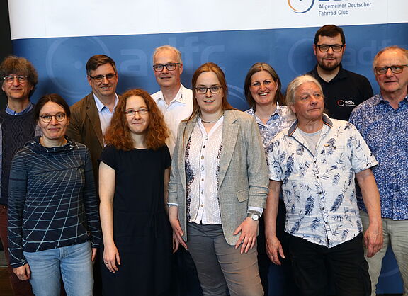 Der Landesvorstand des ADFC NRW, bestehend aus 10 Personen, steht vor einer Stellwand mit ADFC-NRW-Branding.