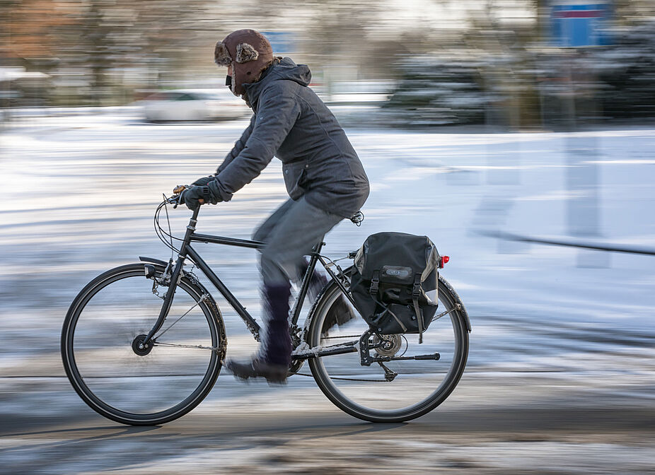Ein Radfahrer im Winter Ein Radfahrer auf einer winterlichen Straße mit Schnee.