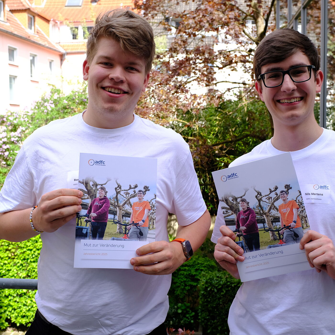 zwei Personen halten einen Bericht hoch. 