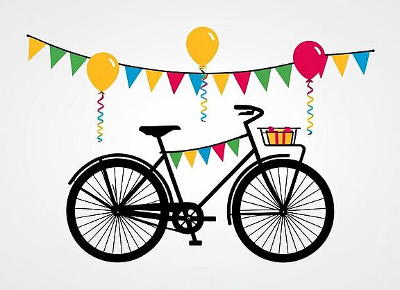 Ein Fahrrad mit bunten Wimpeln und Luftballons und einem kleinen Geschenk im Fahrradkorb vorne